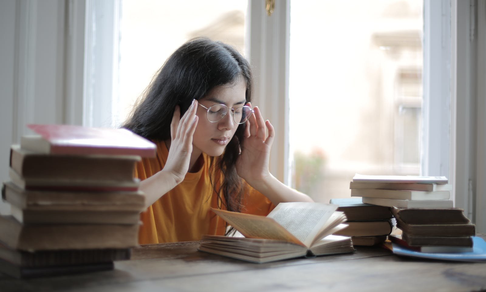 Studentka medytująca z zamkniętymi oczami przed otwartą książką
